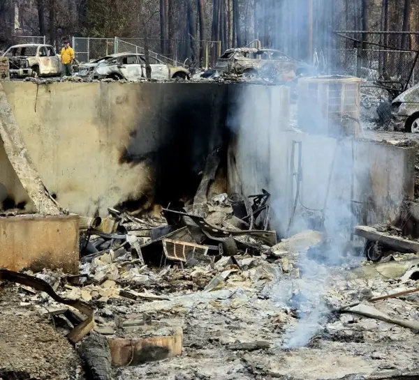 A crew member walking a line of burned vehicles above a foundation that was still putting up smoke.