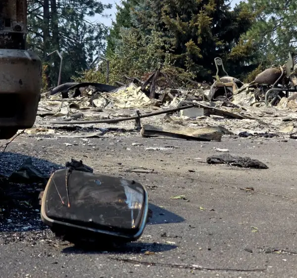 A headlight assembly lying in the street, thrown clear of the house behind it.