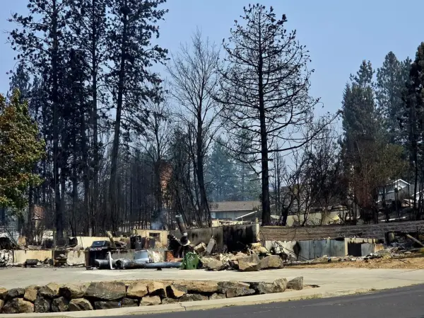 Foundations on the near side of the road, houses standing on the far side.